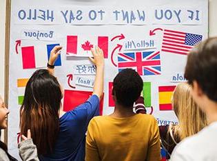 “如果你想说你好”写在一块白板上，上面有几面国旗和语言翻译.